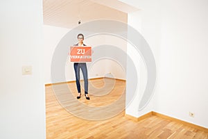 Realtor In Empty Apartment, Holding `zu Verkaufen` Sign photo