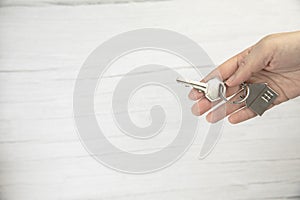 realtor female hand holding new door key to new house on white background top view with copy space, buying new home concept