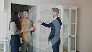 Realtor giving house keys to happy couple who are hugging and laughing enjoying successful deal