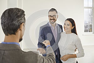 Realtor giving a key to a happy family couple who are buying a new flat or house