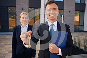 Realtor holding keys in hand while standing near client woman