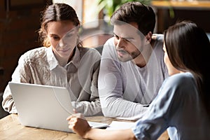 Realtor or insurance broker consulting young couple in cafe