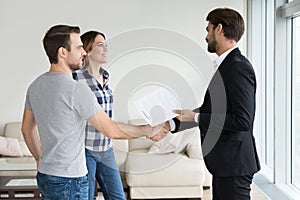 Realtor or landlord handshaking couple tenants make real estate deal