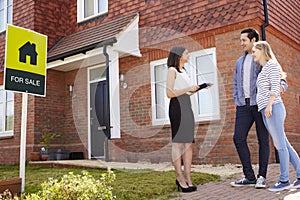 Realtor Outside House For Sale With Young Couple
