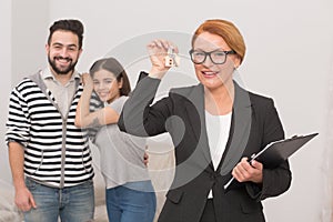 Realtor is playing with keys from new apartment rented by happy young couple.