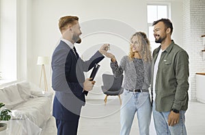 Realtor or real estate agent gives keys to new house or apartment to young family