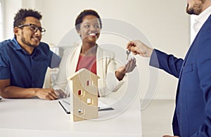 Realtor or real estate agent gives keys to new house to happy young black couple