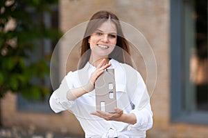 Realtor, real estate sale. Smiling girl with a miniature house in her hands. Home buying advice