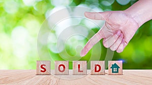 Realtor's hand puts cube with icon house and word SOLD. Concept of selling house, apartment, real estate.