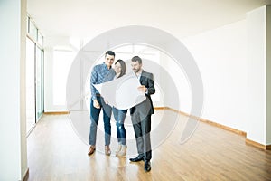 Realtor Showing Architectural Plan To Couple In New House