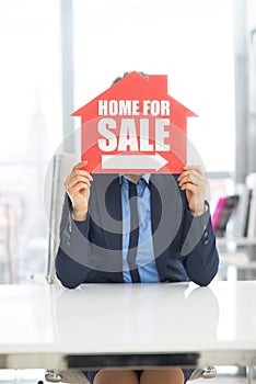 Realtor woman holding home for sale sign