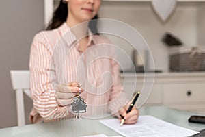 Realtor woman shows keys and writes documents. Close-up of hand. Concept of leasing and mortgage