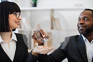 Realtors holding keys from apartment on office background