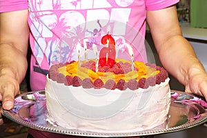 Ð¡ream cake with raspberries and a candle on a tray