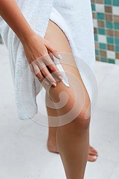 Ð¡ream on leg. Skin Care. Woman hand is applying moisturizing lotion on skin.