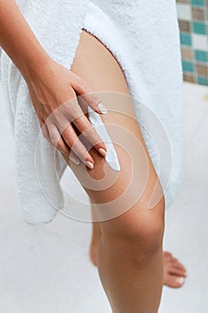 Ð¡ream on leg. Woman hand is applying moisturizing lotion on skin. Beauty and Body care