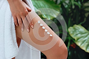 Ð¡ream on leg. Woman hand is applying moisturizing lotion on skin. Beauty and Body care. Protection from cellulite.