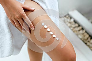 Ð¡ream on leg. Woman hand is applying moisturizing lotion on skin. Beauty and Body care. Protection from cellulite.