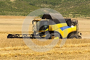 Reaping machine or harvester combine on a wheat field with a very dynamic sky as background photo
