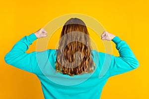 Rear behind portrait of confident person hands flexing biceps curly shiny hair isolated on yellow color background