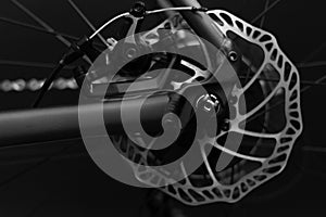 rear bicycle wheel with braking disk and bike components on the black background