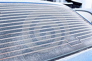 Rear car window covered with frost, warmed defroster