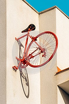 Rear half of red vintage bicycle pinned to the wall casting the shadow of its wheel