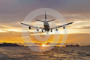 Rear image commercial passenger aircraft or cargo airplane fly over coast of sea after takeoff from airport in evening with golden