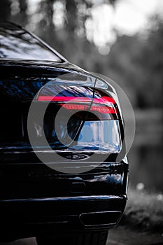 Rear light of a modern black car. Detail of car. Concept of expensive, sports auto.