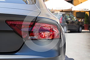 Rear light of parked grey graphite car and blured background