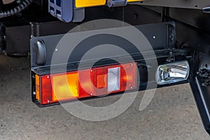 Rear lights of a new truck, close-up. Fragment of the back of the truck. Red brake lights and orange turn signals. Road