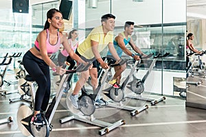 Fit women burning calories during indoor cycling class in a fitness club