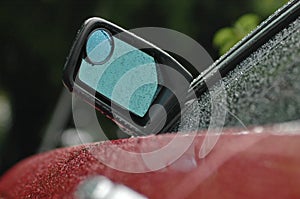 Rear mirror of a brand new red car in rainy day with droplet