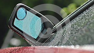 Rear mirror of a brand new red car in rainy day with droplet