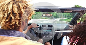 Rear mirror view of handsome black men driving his friends in convertible