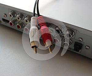 Rear panel of a multimedia player with connection slots and disconnected video cable with tulip plugs