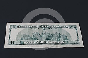 Rear side of old one hundred dollar american currency on black background