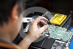 Rear side of technician repairing motherboard of laptop computer