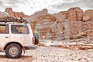 Rear side view of a 4x4 car loading package and wood in the Sahara desert of Tadrart Rouge.