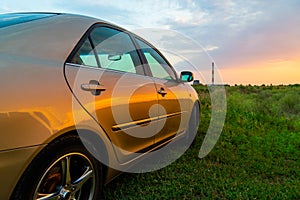 Rear-side view of a luxury car on sunset