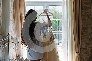 Rear viev bride in lingerie in the morning before the wedding. White negligee of the bride, preparing for the wedding