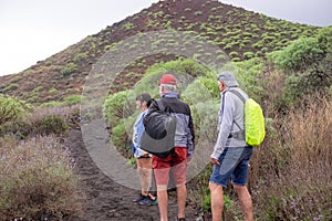 Rear view of active caucasian group of senior friends walking in the nature of Malpais de Guimar in Tenerife island with backpack photo