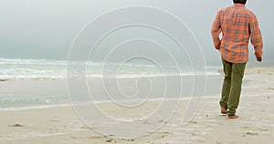 Rear view of active senior African American man with hand in pocket walking on the beach 4k