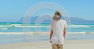 Rear view of active senior African American woman walking on beach in the sunshine 4k