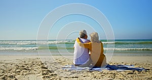 Rear view of active senior Caucasian couple relaxing on the beach 4k