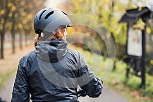 A rear view of active senior woman with bicycle helmet standing outdoors.