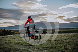 Rear view of active senior woman biker riding bike in nature on autumn day.