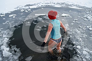 Rear view of active senior woman in swimsuit outdoors in winter, cold therapy concept.