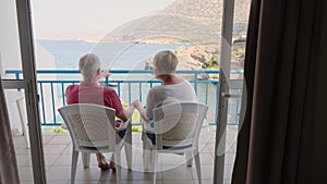 Rear view of adult couple holding hands overlooking the sea and mountains and pointing hands on sea and mountain.