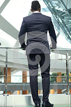 Rear view of African American businessman in suit looking forward, in office building.